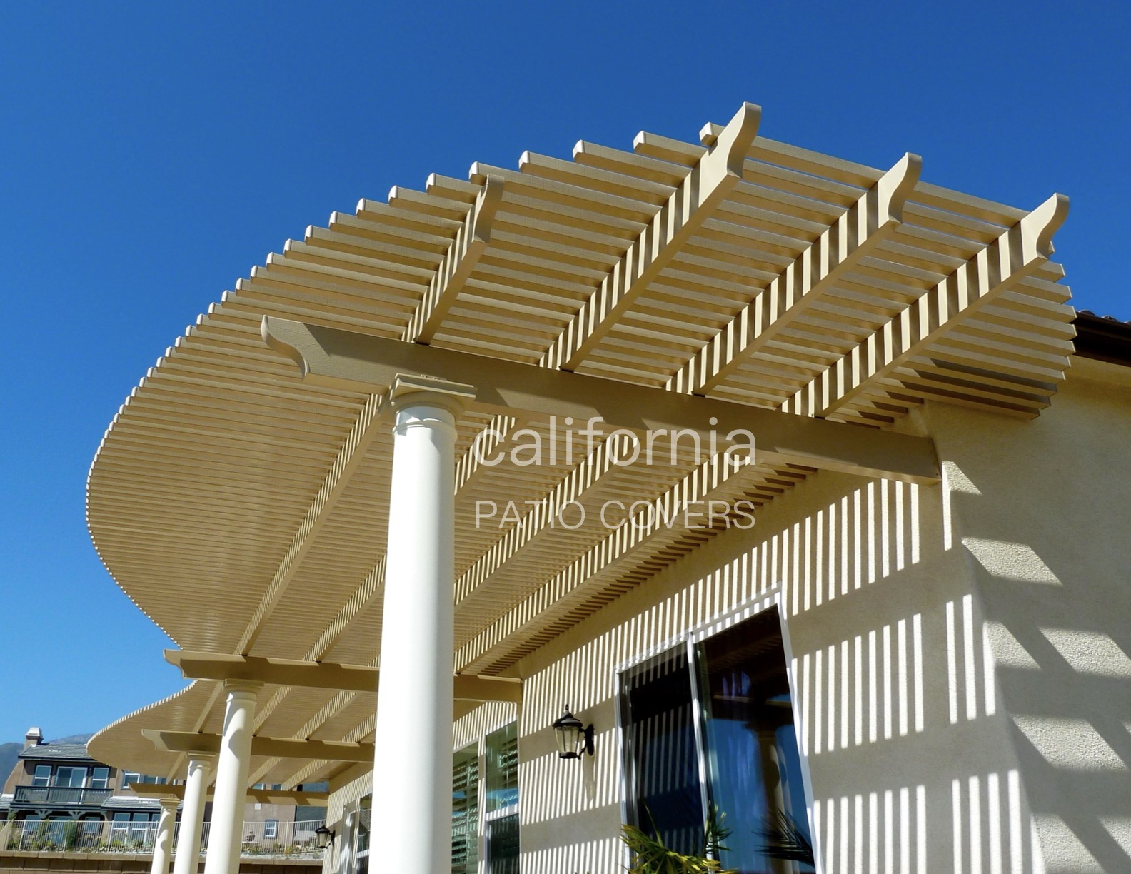 Stylish, curved patio cover constructed with slatted overhead beams, enhancing outdoor living space while providing shade. Ideal for home improvement inspiration.